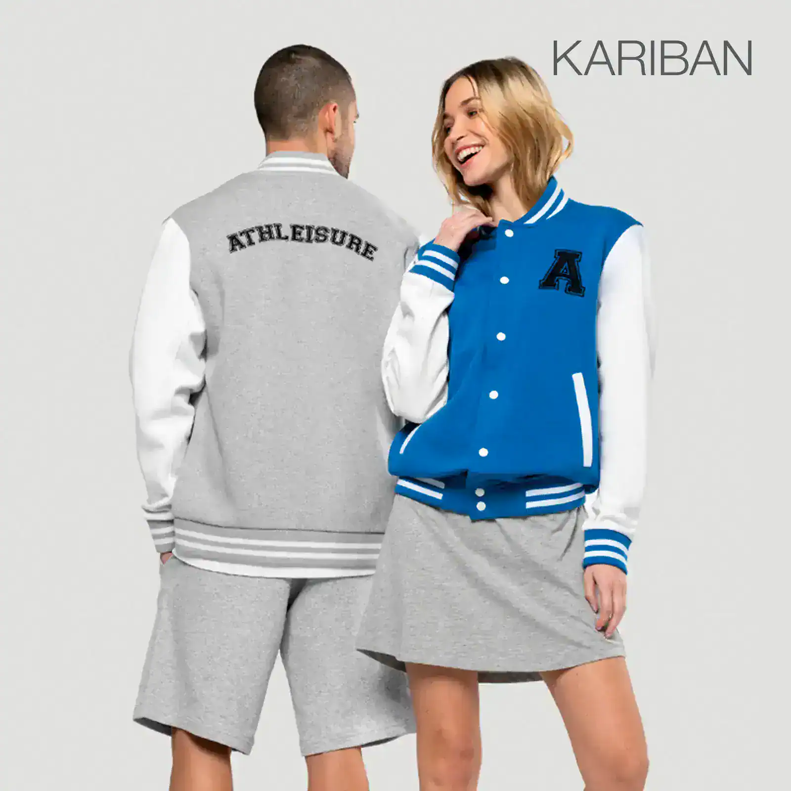 Deux mannequins portent des vêtements de sport de marque Kariban : un homme en survêtement gris et blanc avec « ATHLEISURE » imprimé, une femme en veste de baseball bleu royal avec bandes blanches et jupe grise.